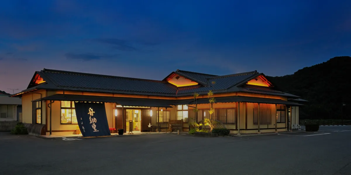 夕闇の中、照明が光る舟納豆本店の外観